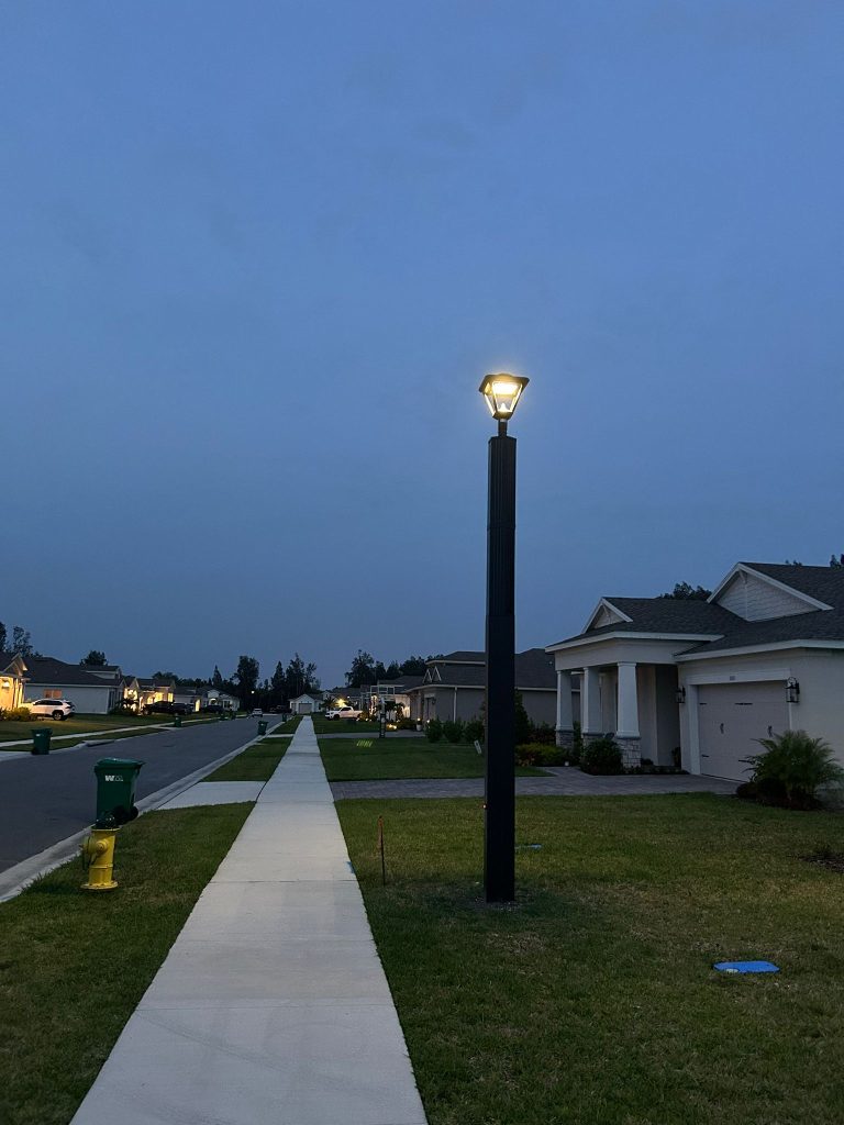 SolarPath decorative solar lantern post light glowing on a residential sidewalk at dusk