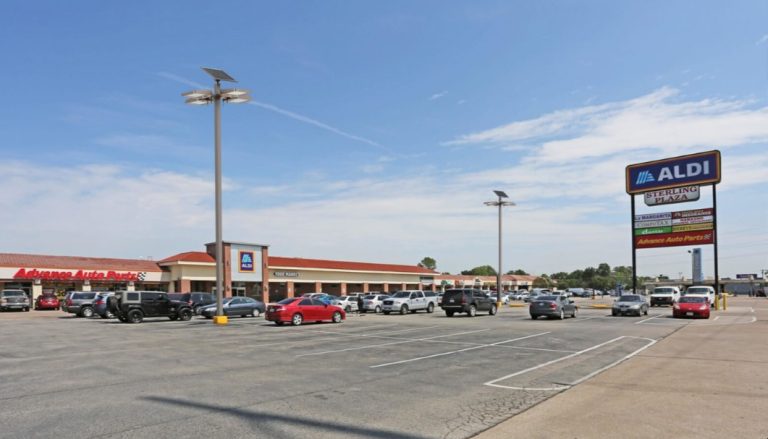 SolarPath dual-panel solar area lights over a retail plaza parking lot