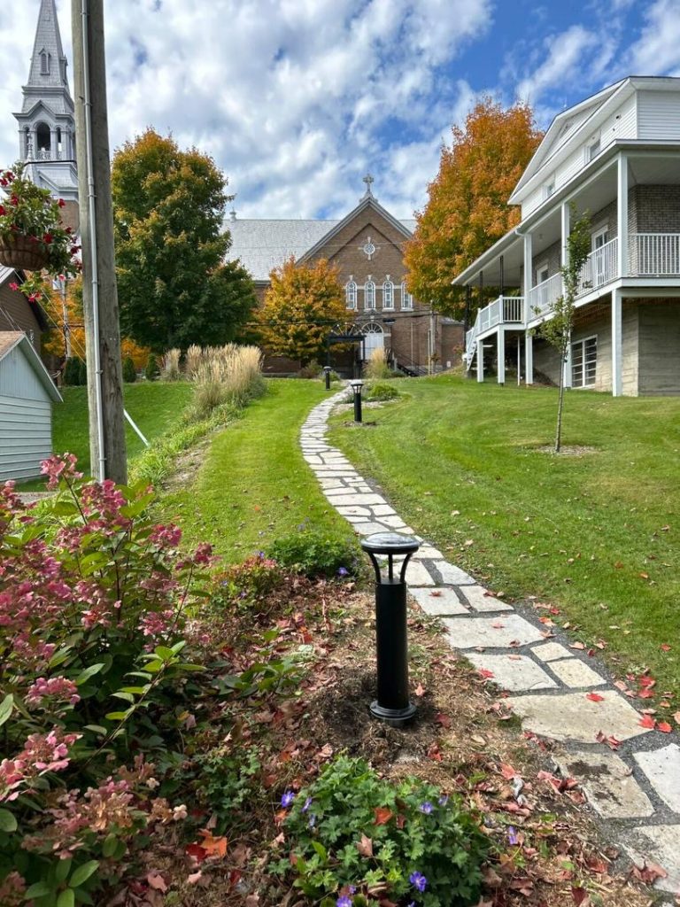 SolarPath solar bollard lighting a stone garden path in autumn
