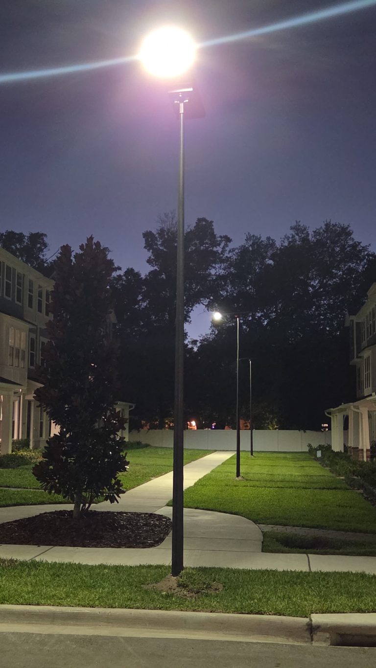 SolarPath solar pole light glowing over a townhome courtyard path at night