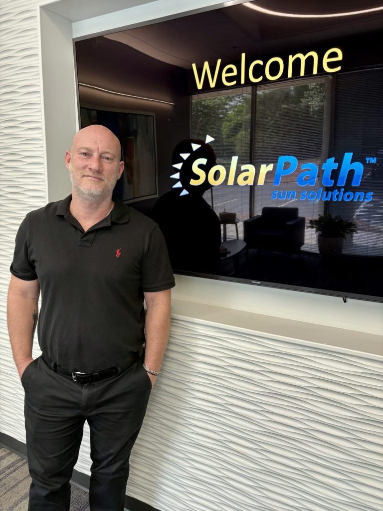 Roy, owner of SolarPath Sun Solutions, at the company welcome sign